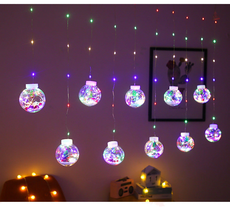Lichtervorhang mit Weihnachtskugeln und Weihnachtsfiguren
