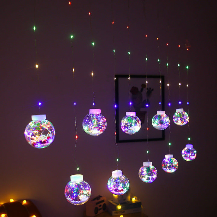 Lichtervorhang mit Weihnachtskugeln und Weihnachtsfiguren